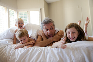 Father and children relaxing on bed