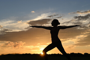 Close-up of backlit young woman practicing yoga during sunrise