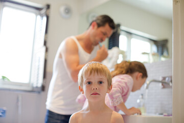 Father and children brushing teeth in bathroom