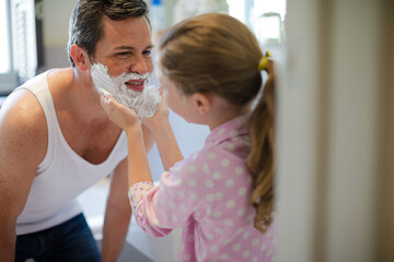 Girl rubbing shaving cream on father's face