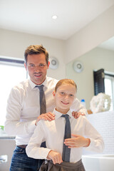 Father and daughter tying ties in bathroom