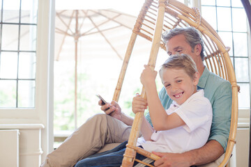 Father and son sitting in wicker chair