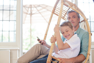 Father and son sitting in wicker chair