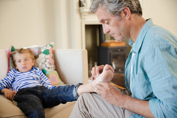 Father bandaging son's foot