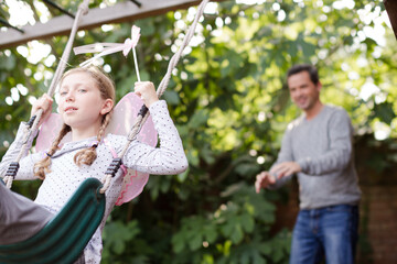 Father pushing daughter in swing