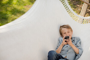 Boy using cell phone in hammock
