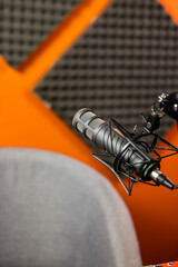 Microphone and empty chair with sound proofing on the walls in professional audio podcasting singing recording studio