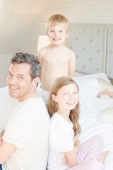 Obraz premium Father and children smiling on bed