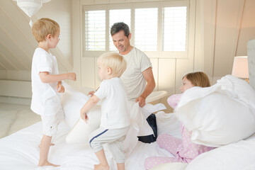 Obraz premium Father and children having pillow fight