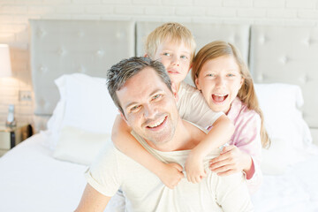 Father and children hugging in bedroom
