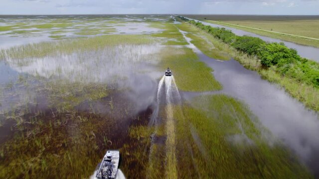 Aerial drone view overlooking airboats, driving on a lake in Everglades, Miami