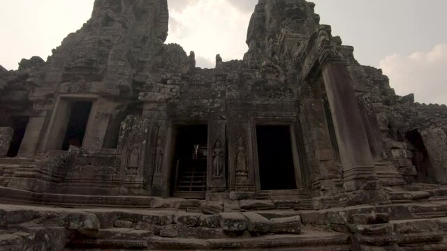 Historical building facade of Bayon Temple within Angkor complex, Cambodia, tilting upward shot
