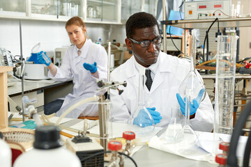 Man proffesional lab scientist in glasses working with reagents and test tubes in laboratory