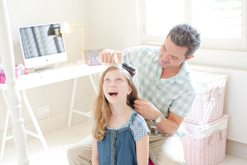 Obraz na płótnie Canvas Father combing hair to his daughter