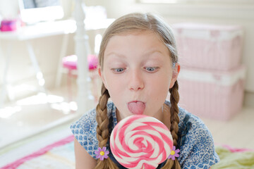 Girl licking lollipop in bedroom