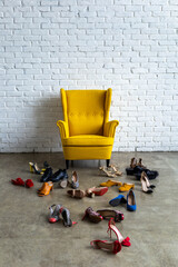 Empty white loft room with fashion yellow armchair surrounded by many bright female shoes mess