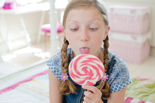 Girl licking lollipop in bedroom