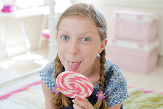 Girl licking lollipop in bedroom