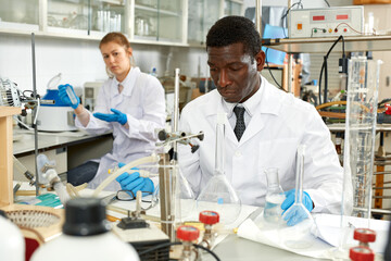 Proffesional male lab technicians with different glass tubes, girl on background