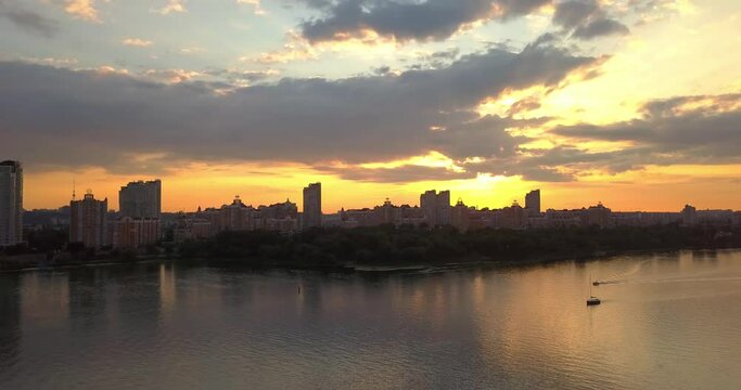 Aerial drone view of sunset over Dnipro river with boats and bank of Obolon district in Kiev city, Ukraine