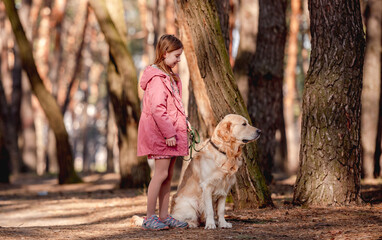 Little girl with golden retriever dog in the wood