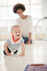 Mother watching baby boy crawl in living room