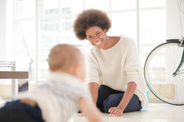 Obraz premium Mother watching baby boy crawl on floor