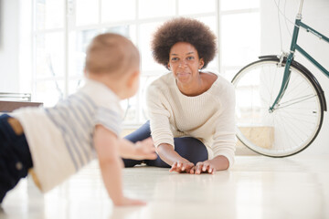 Mother watching baby boy crawl on floor