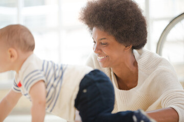 Mother watching baby boy crawl on floor