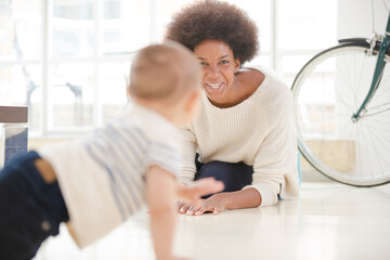 Obraz premium Mother watching baby boy crawl on floor