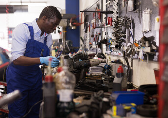 Afro american worker in overalls inspects a motorcycle engine. High quality photo