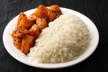 Homemade Asian vegetarian meal- healthy organic white rice served with spicy potato roast curry, Indian cooking.