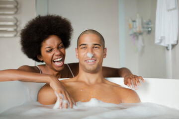 Woman playing with boyfriend in bubble bath