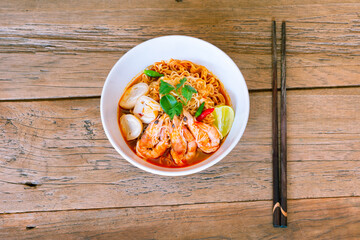 Spicy Instant noodle Tom Yum Goong Topveiw with chop stick on wood back ground