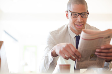Businessman reading newspaper and drinking coffee