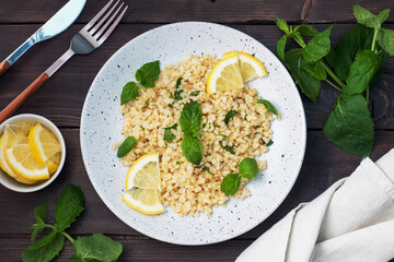 Boiled bulgur with fresh lemon and mint on a plate. A traditional oriental dish called Tabouleh....