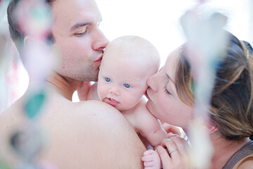 Parents kissing baby girl's cheeks