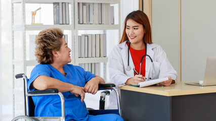 Obraz premium Asian woman doctor writing note and near with elderly female as sitting on wheelchair both of them are smiling look to happy and comfortable at hospital in the morning