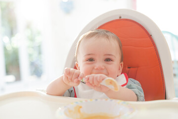 Baby boy eating in high chair