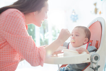 Mother feeding baby boy in high chair