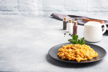 Delicious Asian pilaf, stewed rice with vegetables and chicken on a plate. gray concrete background. copy space.