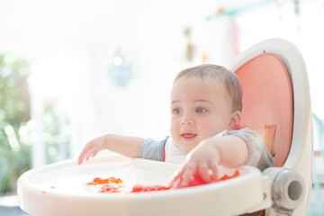 Baby boy eating gelatin dessert in high chair