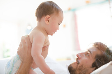 Father playing with baby son on sofa