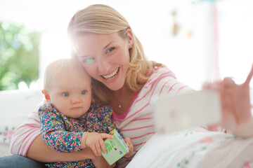 Mother taking self-portrait with baby girl