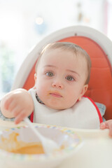 Baby boy eating in high chair