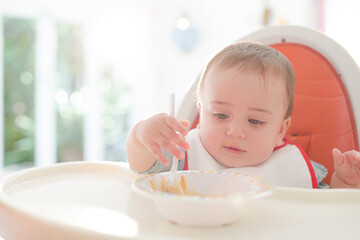 Baby boy eating in high chair