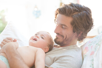 Father laying with baby boy on bed