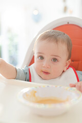 Baby boy eating in high chair