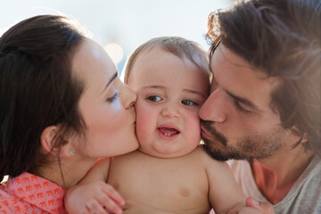 Parents kissing baby boy's cheeks