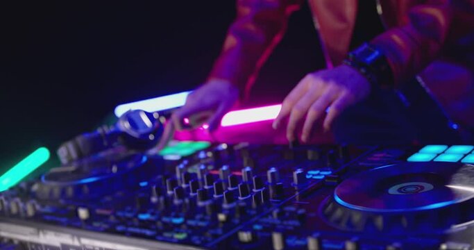 Close-Up of Dj Mixer Controller Desk in Night Club Disco Party. DJ Hands touching Buttons and Sliders Playing Electronic Music . Amazing Close Up of DJ Hands Mixing and Scratching Music on Vinyl Plate